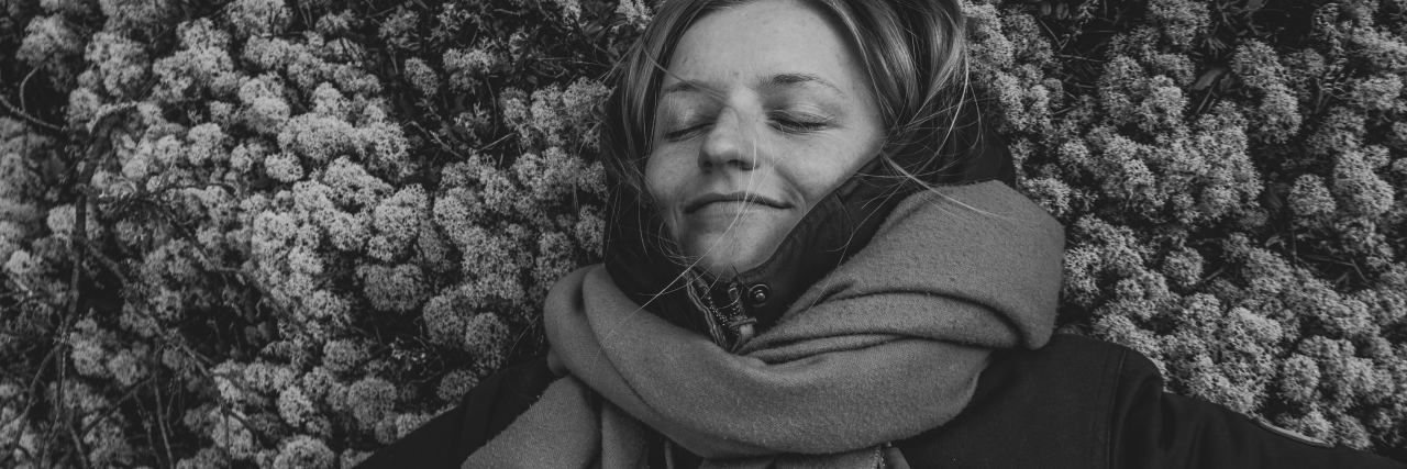 black and white photo of woman lying on ground smiling with eyes closed