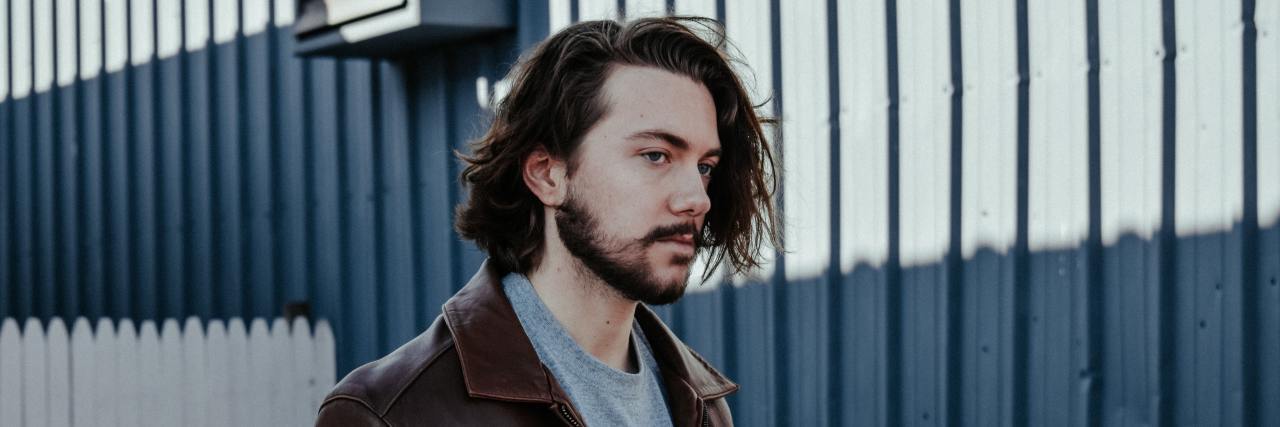 How I Deal With the 'Buyer's Remorse' of My OCD man with shaggy brown hair in a leather jacket walking outside