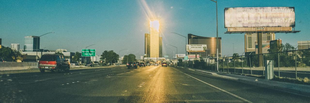 Why Asking Someone Struggling With Mental Health to Smile Is Harmful photo of the sun shining against a highway, with a billboard to the right