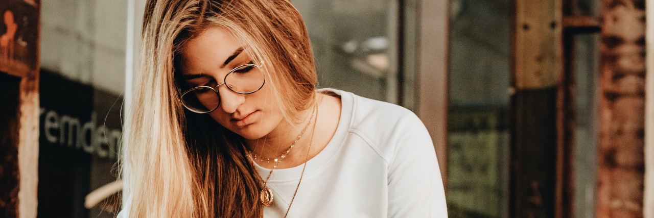Feeling Like I Can't Catch a Break With Mental Illness photo of blonde woman in glasses looking down while opening or closing back