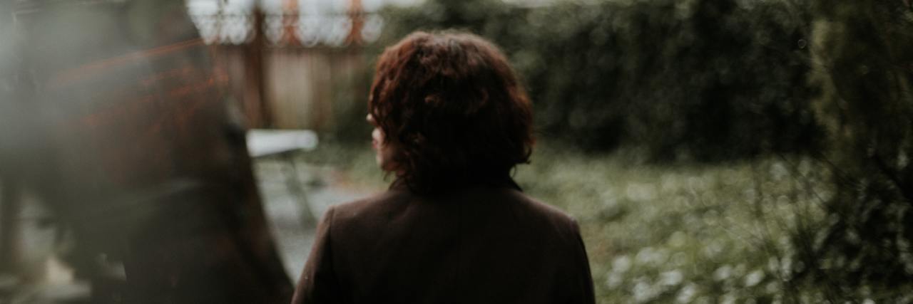 photo from behind of person looking out over garden in dull light