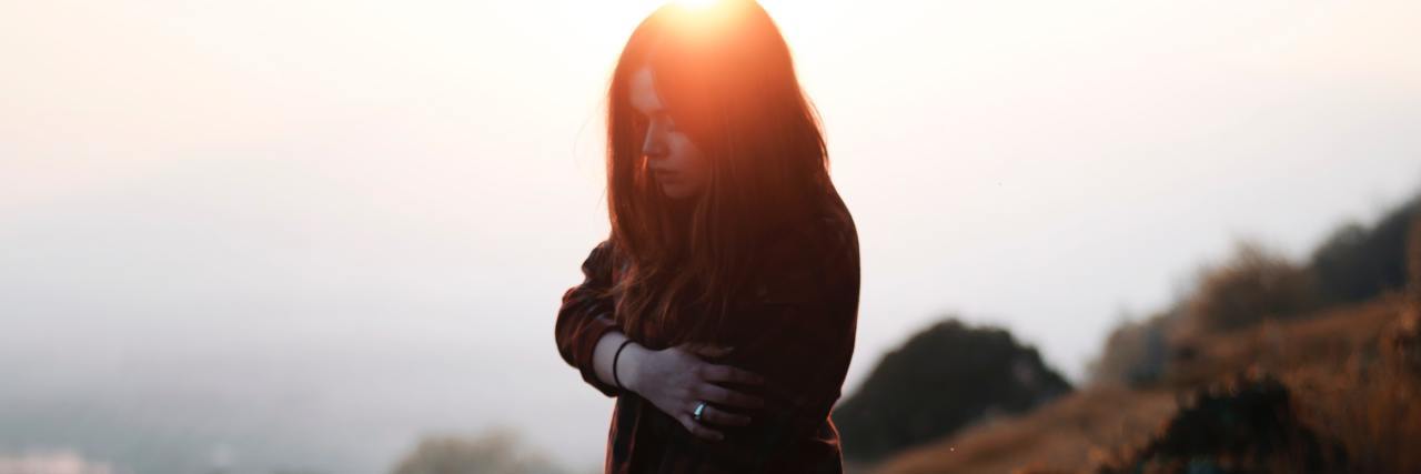 It's OK to Grieve After Losing a Relationship or Breaking Up woman in a red flannel and gloves standing on a hill, looking down with a sorrowful face