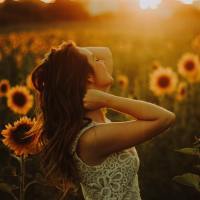 Woman standing in a sunflower garden at sunset.