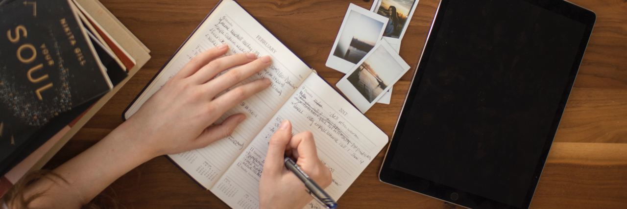 What Is Ambition? hands writing in notebook with coffee and laptop on table