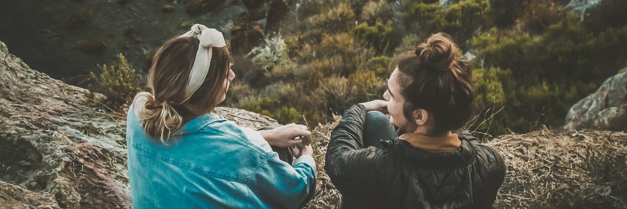 What to Say to Help Someone Who Was Abused as a Child photo of two women sitting on hillside over ocean having conversation
