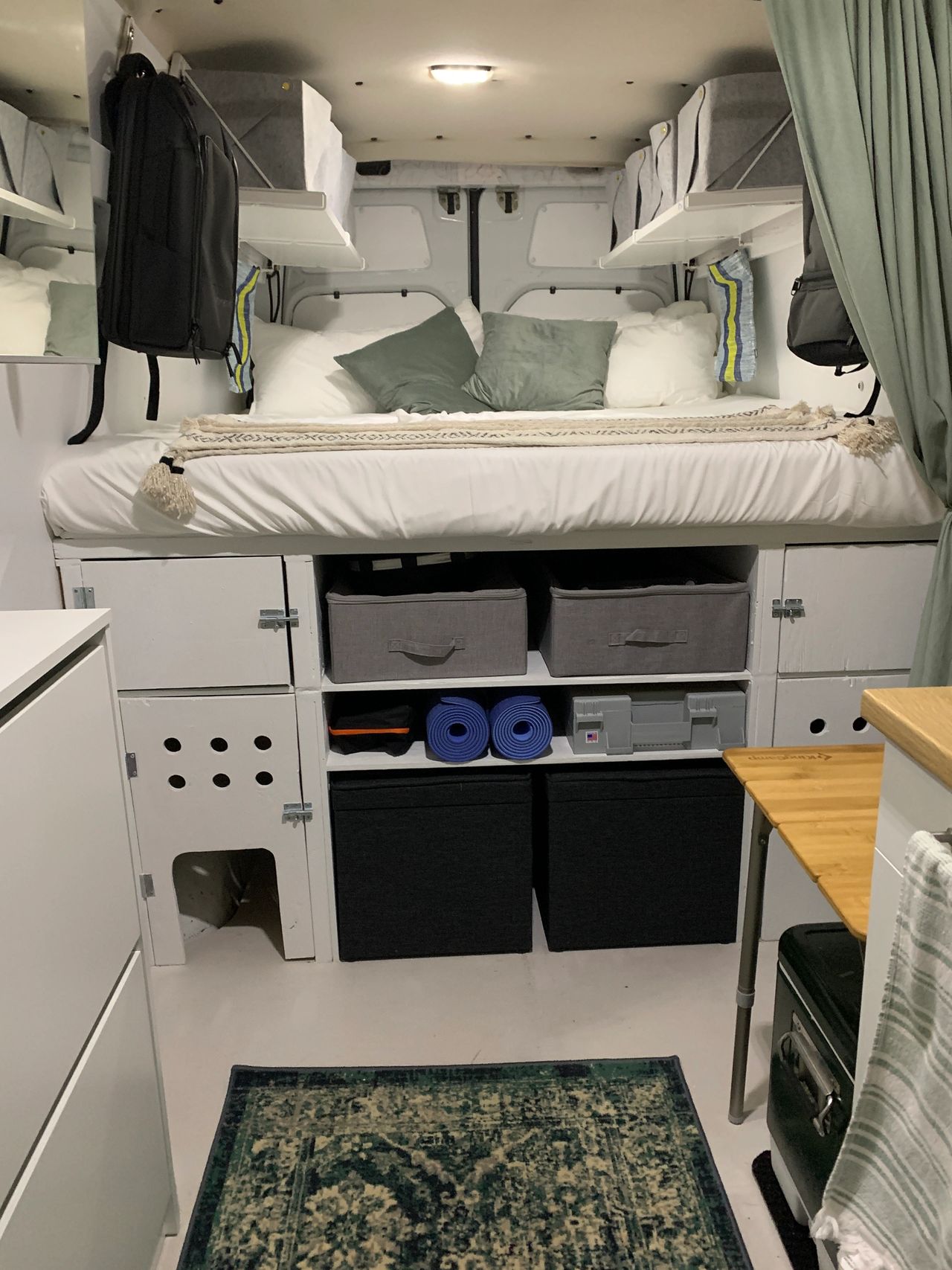 Interior of van with bed in the back, set up for van life with chronic illness.