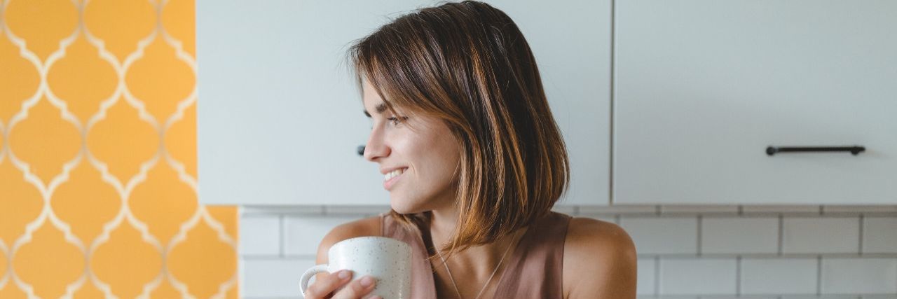 Things You Can Do to Distract Yourself From Coronavirus News White woman with short brown hair looked to the left while holding a mug with the title text: 20 Things You Can Do to Distract Yourself From Coronavirus News