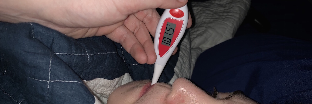 A young boy with a thermometer in his mouth