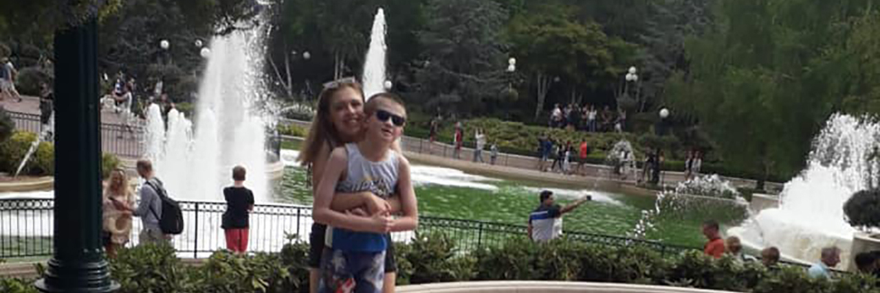 Accepting My Autistic Brother Freya and her brother Dian outdoors with a fountain in the background.