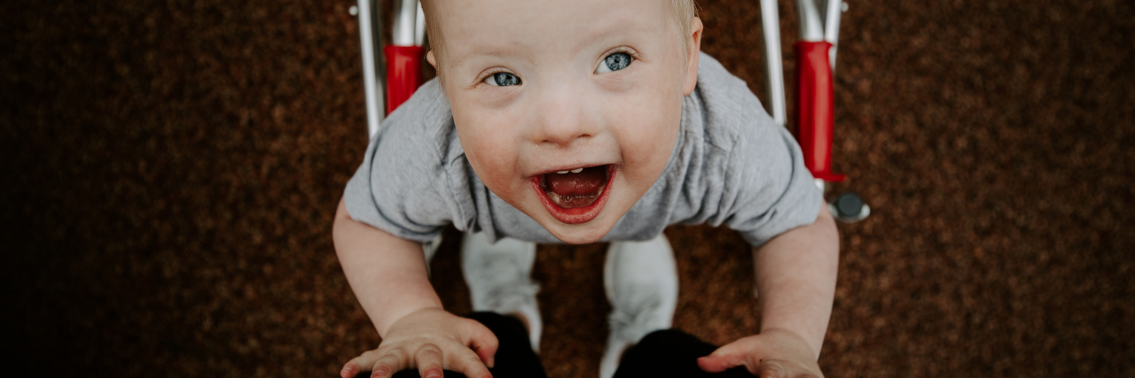 Protecting Children With Down Syndrome From COVID-19 Medical Rationing Madison's son, who has Down syndrome, smiling up at the camera.