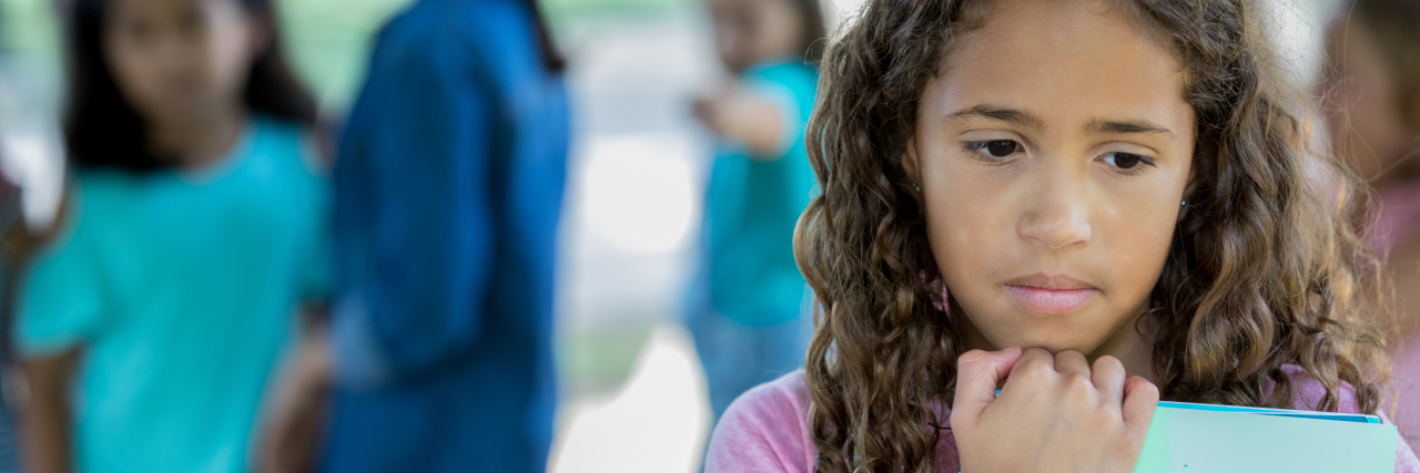 5 Common Triggers for Adults With Learning Disabilities Sad little girl standing outside school with bullies.