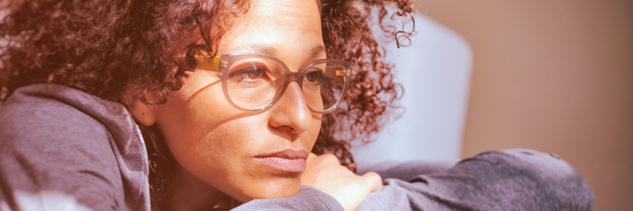 The Difference Between COVID-19 and a Chronic Illness Flare Woman on her sofa, worried about COVID-19.