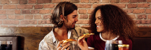 Couple enjoying eating pizza at cafe.