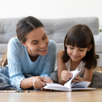 Mother reading book with young daughter.