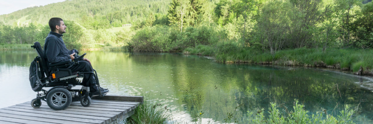 The Lessons Duchenne Muscular Dystrophy Has Taught Me Man with Duchenne muscular dystrophy in power wheelchair on dock looking at lake.
