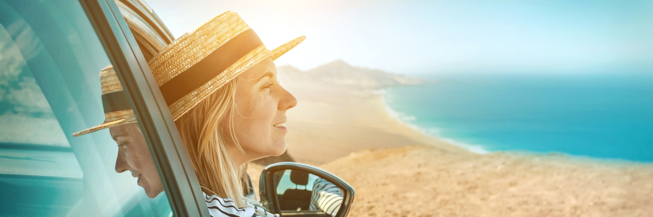 Traveling With Fibromyalgia: 8 Things to Make Road Trips Easier Woman traveling with fibromyalgia, looking out the window at the ocean.