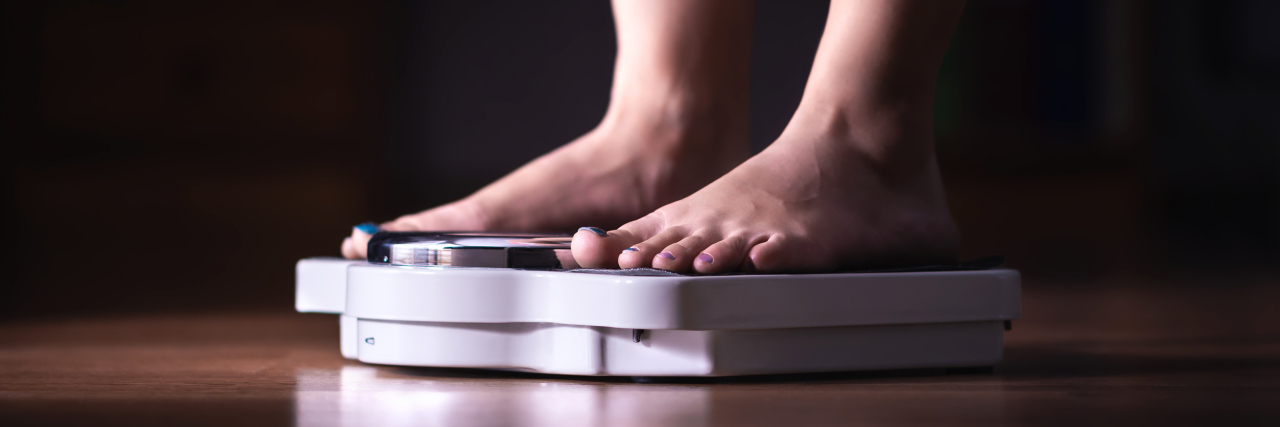 close up photo of feet on scale on a hardwood floor