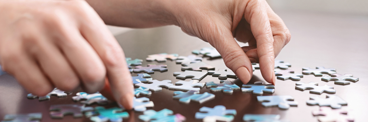 woman's hands putting pieces of a puzzle together on a table