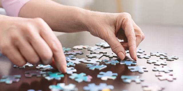 woman's hands putting pieces of a puzzle together on a table