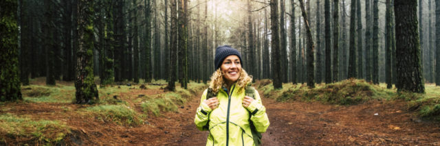 woman in the middle of a hiking trail smiling