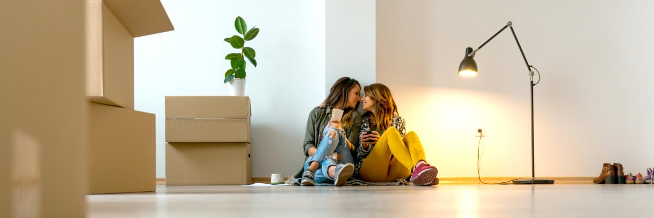 lesbian couple sitting in a new apartment, kissing