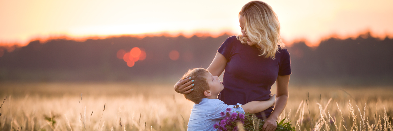 Parenting With Scleroderma Boy hugging his mother in a summer meadow.