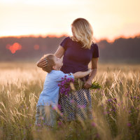 Boy hugging his mother in a summer meadow.