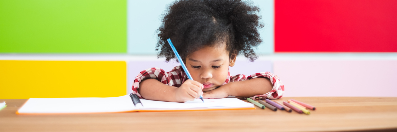 Feeling Anxiety About All-of-a-Sudden Homeschooling? little girl in front of a colorful bookshelf writing on paper