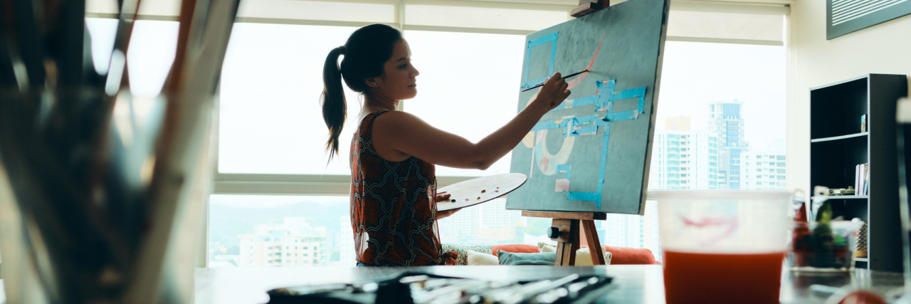 COVID-19: Don't Feel Guilty If Your Self-Isolation Isn't Productive A woman painting in her home