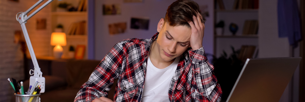 10 Study Tips for Students With ADHD young man sitting at a desk doing homework, frustrated