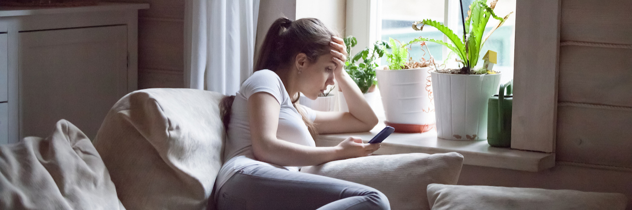 My Eating Disorder Started With an App That Counts Calories Young woman with hand on her head and looking at her cell phone