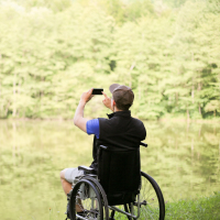 a man sitting in a wheelchair taking a photo of nature