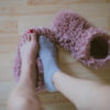 A woman in one sock putting on her slippers