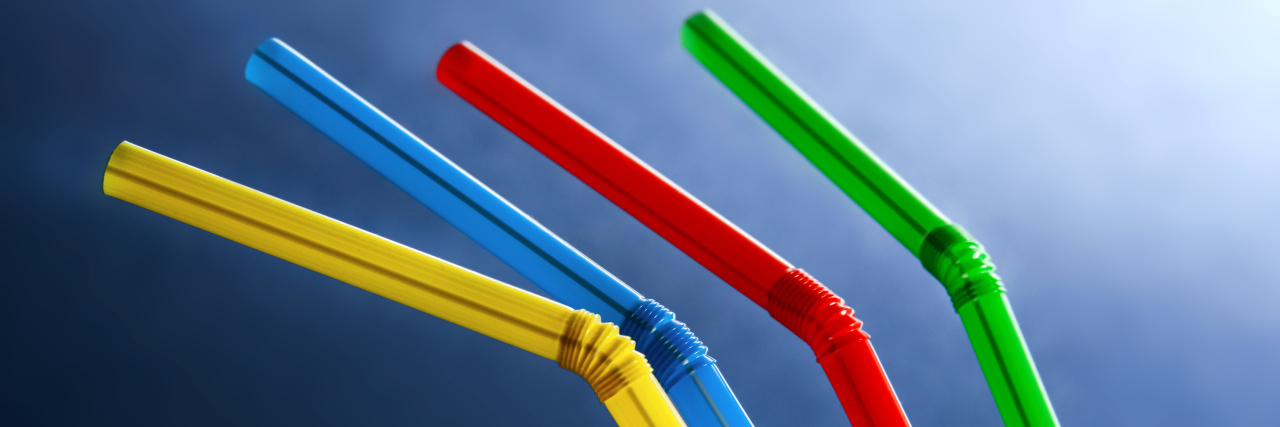 How Banning Plastic Straws Affects Disabled People Bendy plastic drinking straws on blue background.
