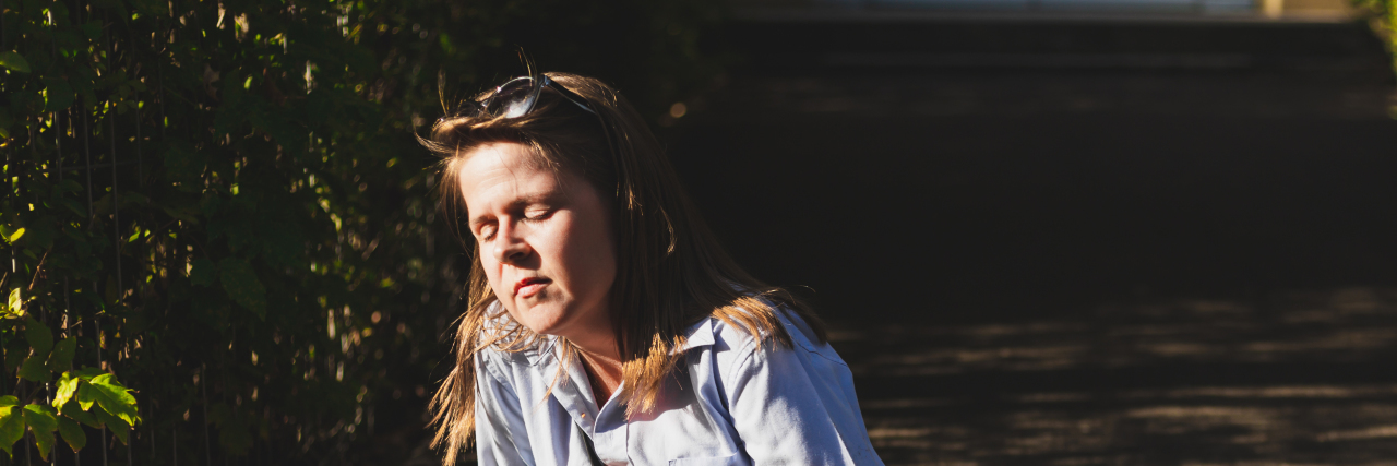 Young woman sitting on the ground about to have a seizure.