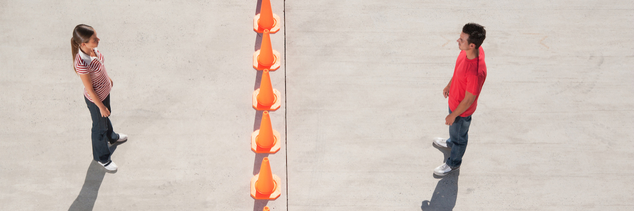 Man and woman on either side of row of traffic cones looking back