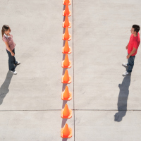Man and woman on either side of row of traffic cones looking back