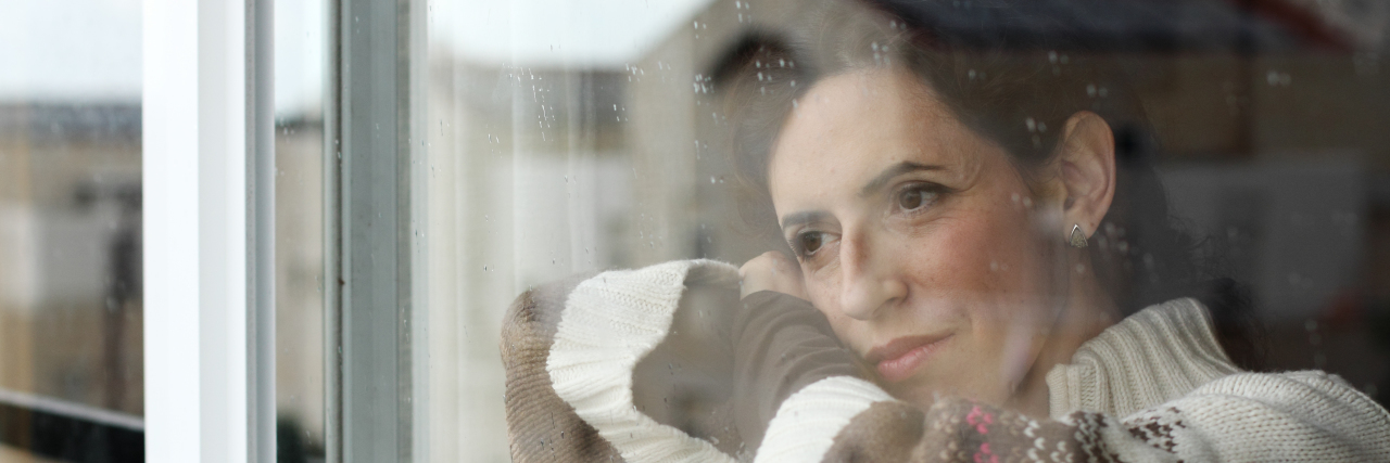 It's OK to Be Scared of Getting the Coronavirus Woman looking sadly out a window.