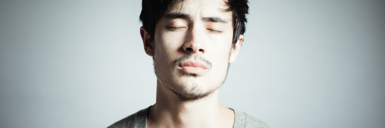 An asian man closing his eyes