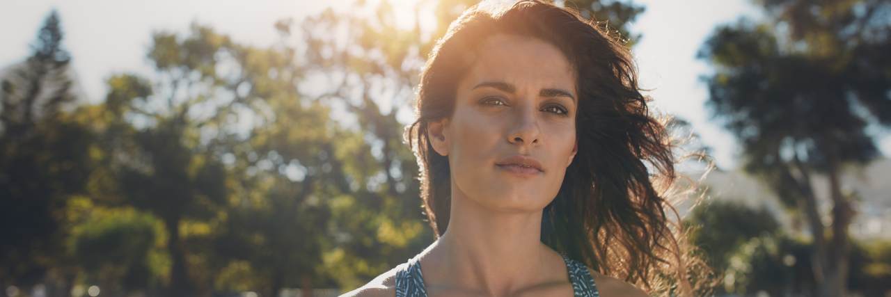 10 Things You Can Do to Cope With the Anniversary of a Trauma woman in a sports bra out in the park looking boldly ahead