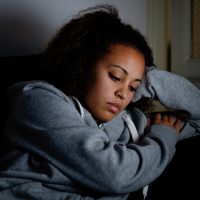 Sad black woman lying on the couch at night