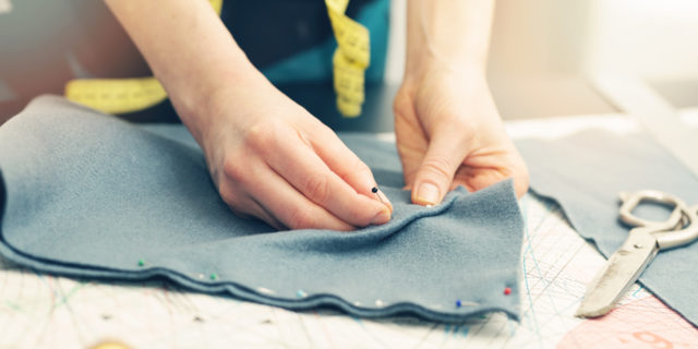 tailor marking the fabric with sewing pins