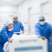 Nurse and doctor in a hurry taking patient to operation theatre. Patient on hospital bed pushed from surgeon to emergency theatre. Team of doctors and surgeon rushing patient. (Nurse and doctor in a hurry taking patient to operation theatre. Patient o