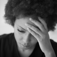 Tired african american woman touching her forehead and looking down.