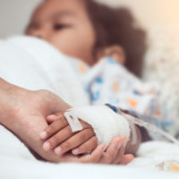 Parent holding the hand of a child in the hospital