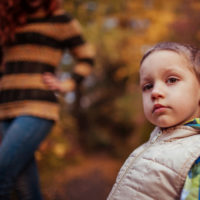 little boy outside in the fall with a vest on