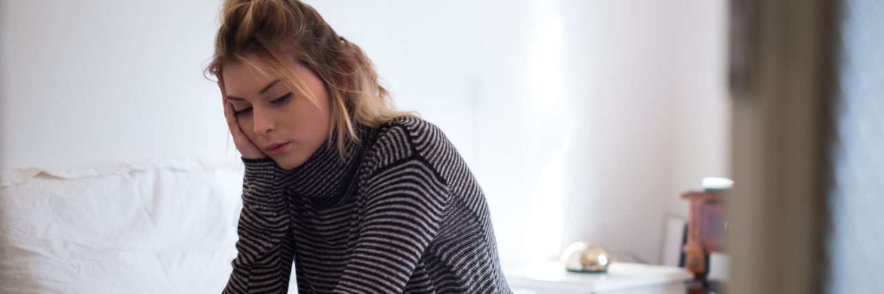 When Mental Illness Makes It Hard to Practice Prevention for COVID-19 woman sitting on the edge of her bed looking down, sad