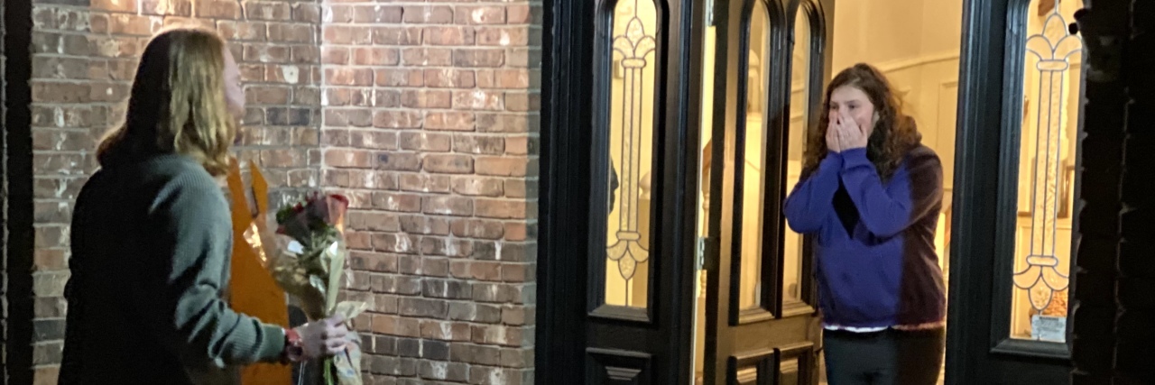 My Daughter With Autism's 'Promposal' Was 15 Years in the Making A young man standing at a young woman's door with a "promposal" sign.