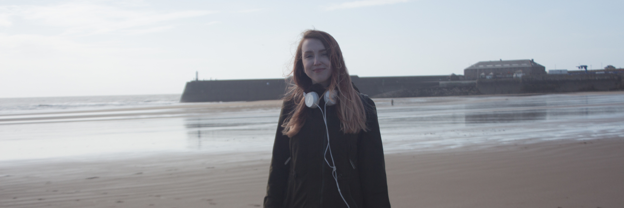Traveling as a Young Disabled Woman With Crohn's Disease Amy Aed on a beach in Wales