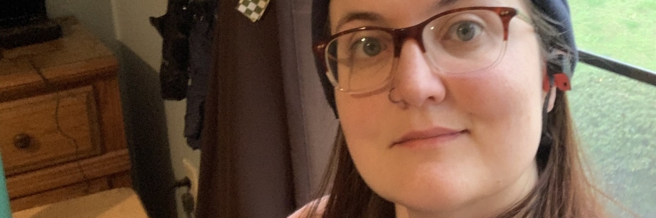 Why I'm Struggling With Switching to Online Therapy Due to COVID-19 photo of contributor posing by window wearing hat and glasses